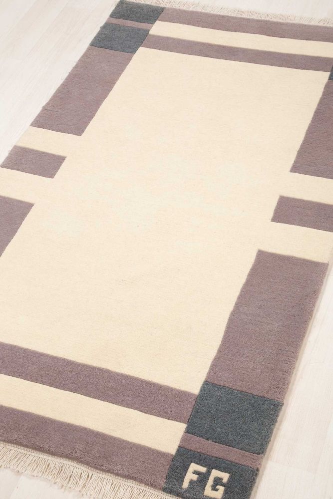 Handknuten tjock ullmatta med vit spegelmönster och en bård som är indelad i olika grå nyanser